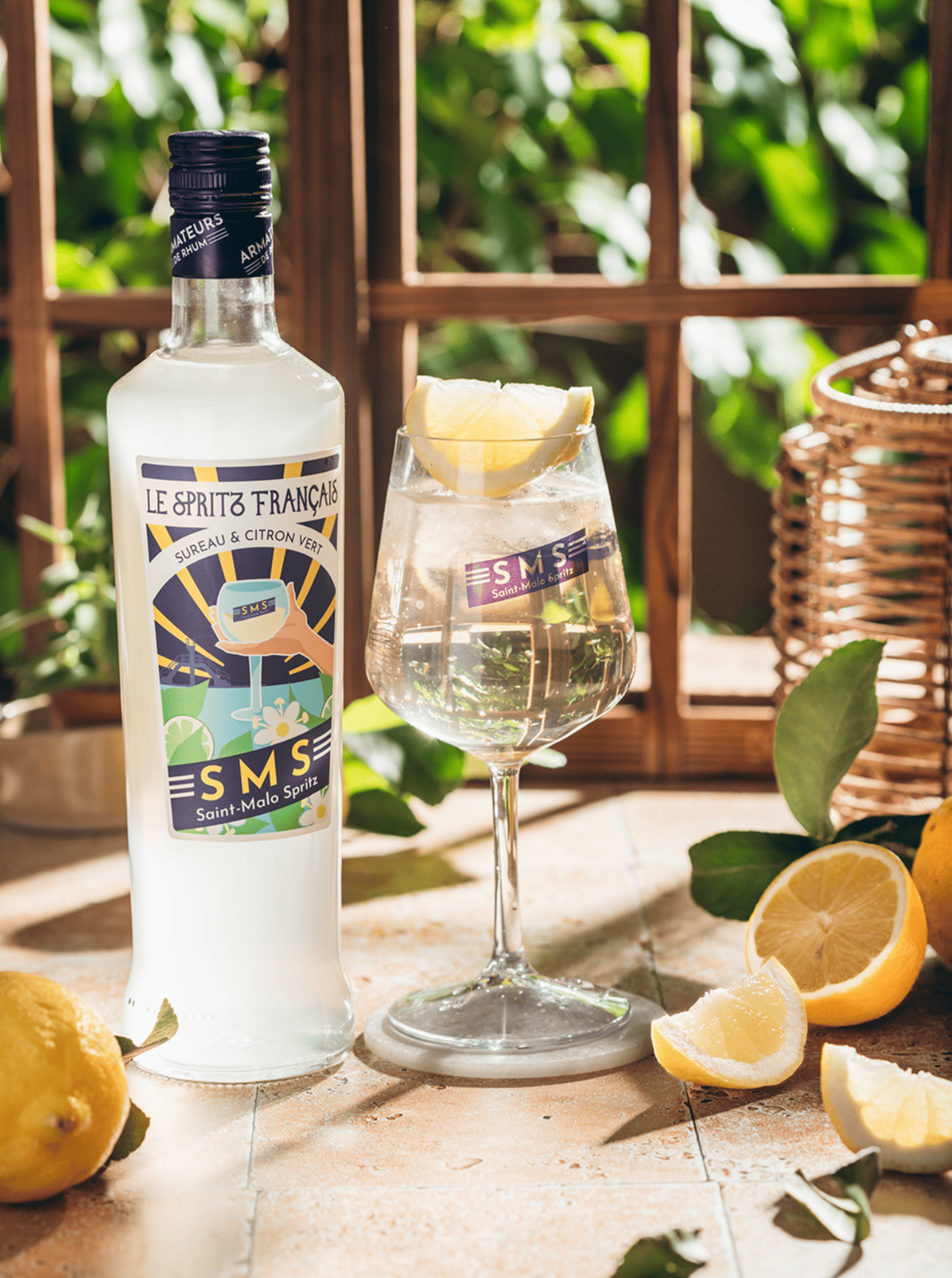 Bouteille Le Spritz Français SMS avec verre cocktail citronné sur table en bois – spiritueux breton artisanal.