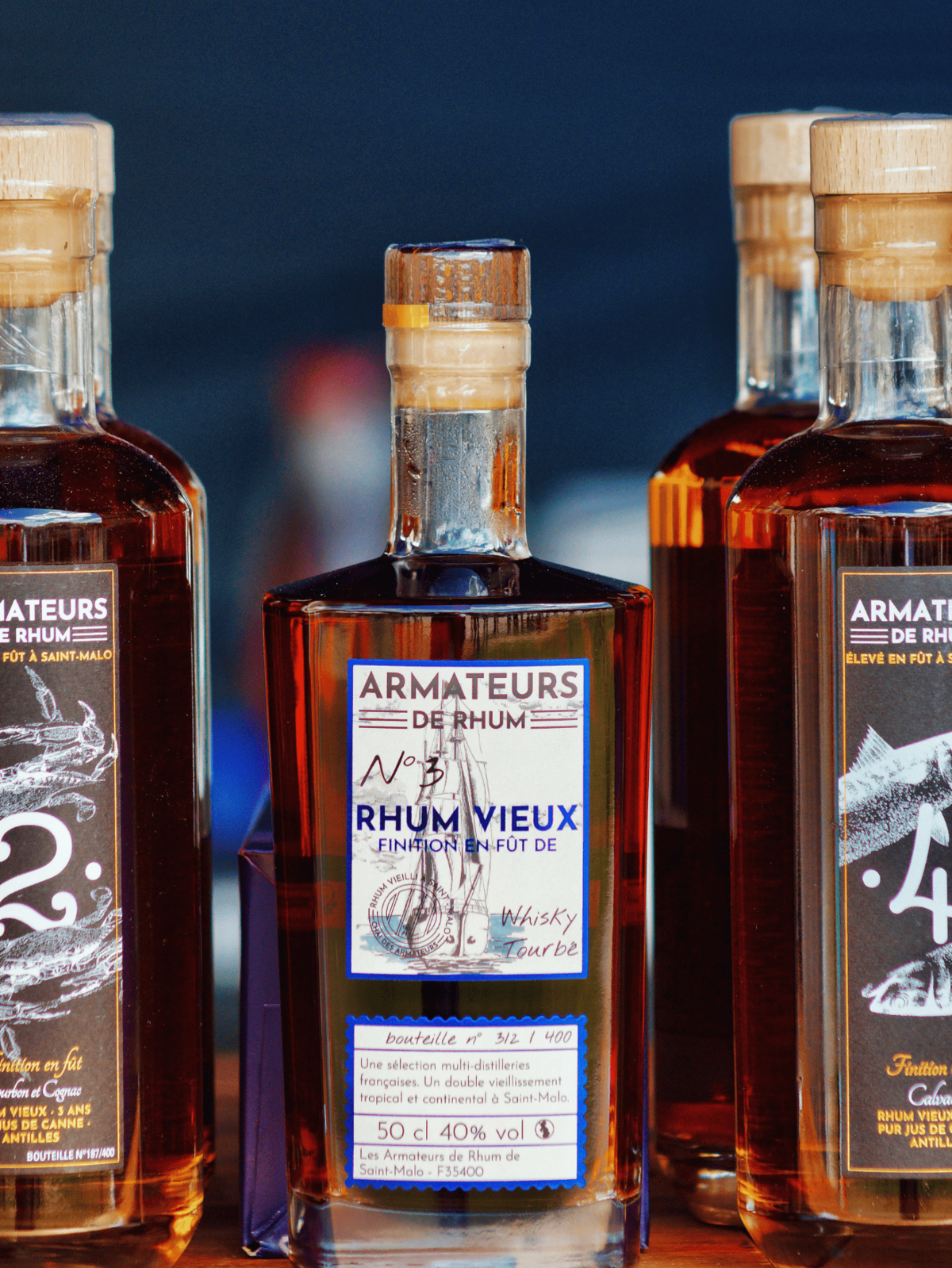 Bouteilles de Rhum Vieux Armateurs exposées sur fond sombre – rhum breton vieilli en fût.