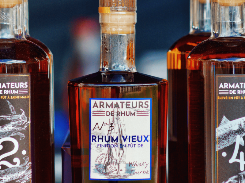 Bouteilles de Rhum Vieux Armateurs exposées sur fond sombre – rhum breton vieilli en fût.